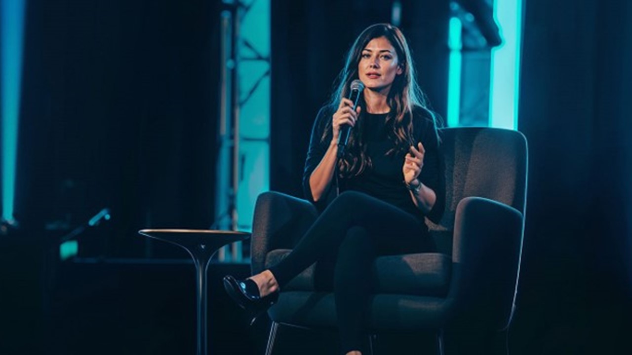 Une femme assise tenant un micro en donnant une conférence