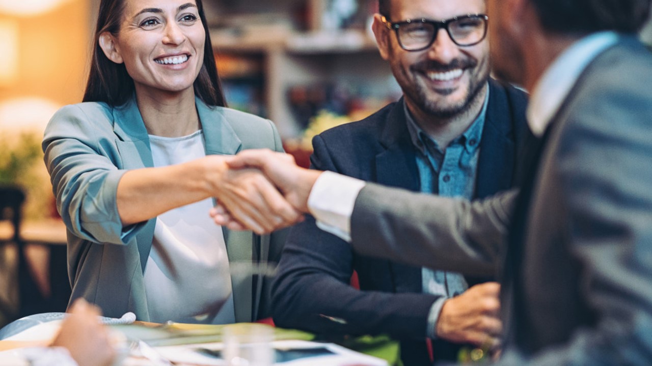 Trois personnes autour d'une table se serrant la main