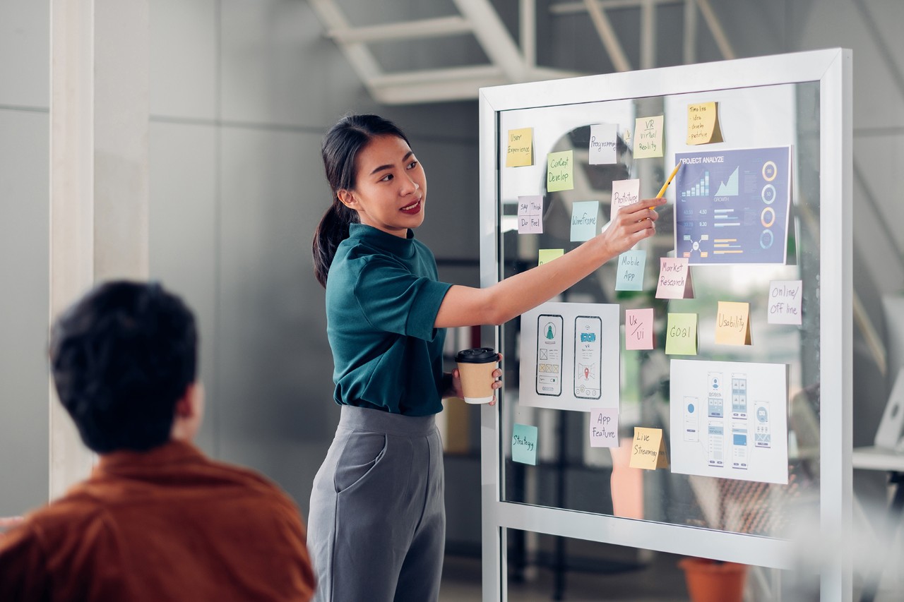 A woman presentation information on a board to a man